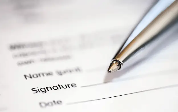 Close-up of a pen positioned on a form with blank signature and date fields, symbolizing the importance of documentation, commitment, and formal agreements of health care directive