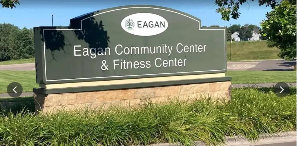 Eagan Community Center & Fitness Center outdoor entrance sign surrounded by grass with a sunny suburban neighborhood in the background.