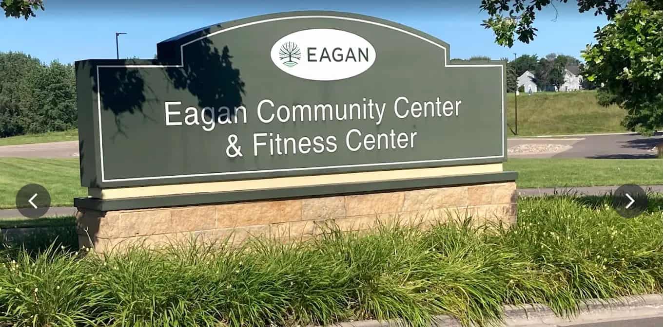 Eagan Community Center & Fitness Center outdoor entrance sign surrounded by grass with a sunny suburban neighborhood in the background.