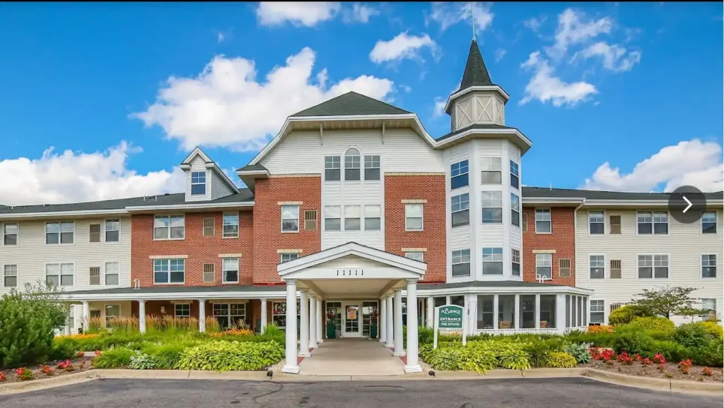 Front entrance of The Rivers senior living community in Burnsville, Minnesota, featuring brick facade, white columns, and landscaped gardens.